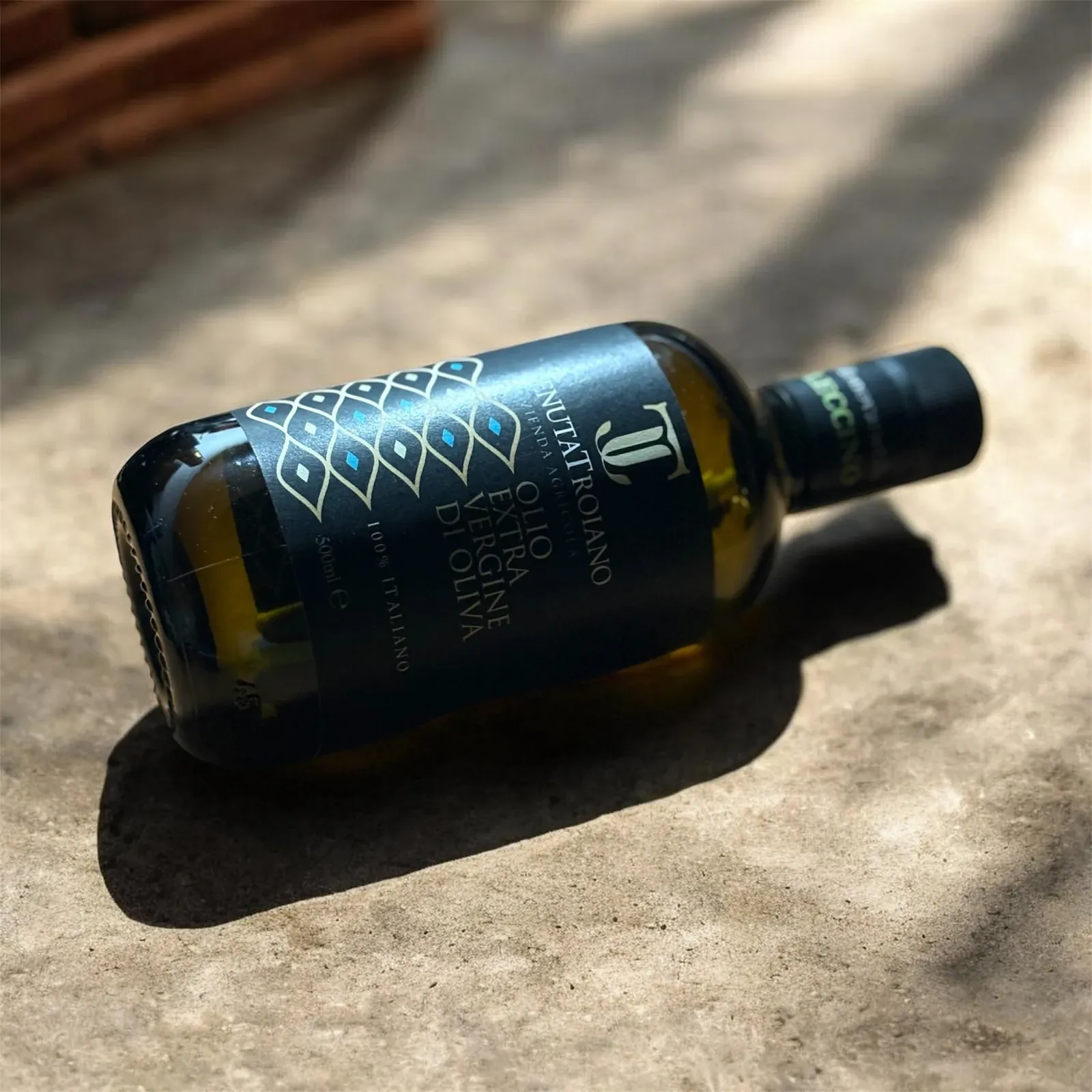 Bottiglia da 500 ml Tenuta Troiano distesa su un tavolo di legno.
